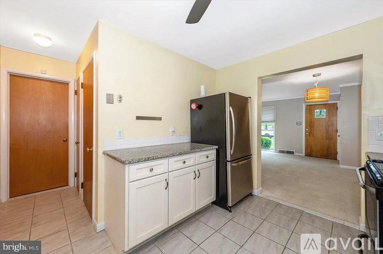 A kitchen with a black fridge and white cabinets.