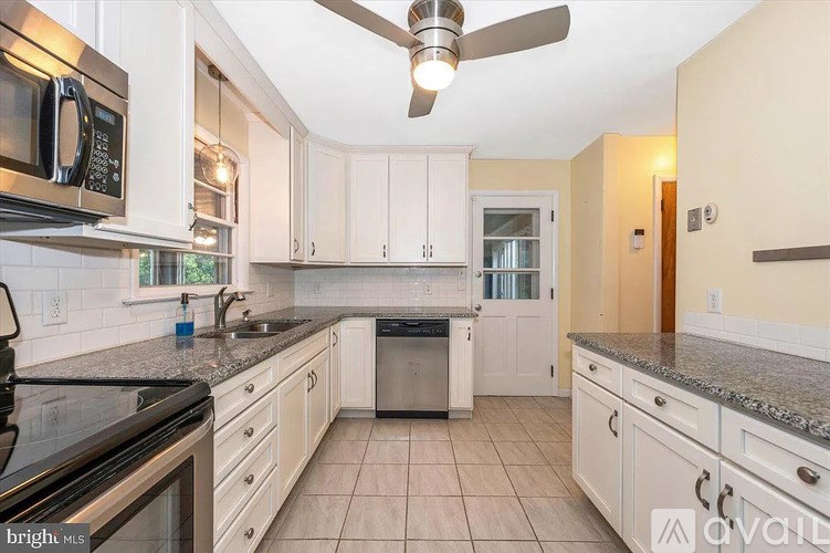 A kitchen with white cabinets and a black stove top oven.
