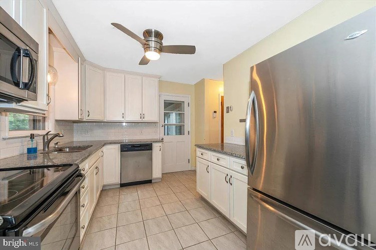 A modern kitchen with a stainless steel refrigerator and a fan on the ceiling.