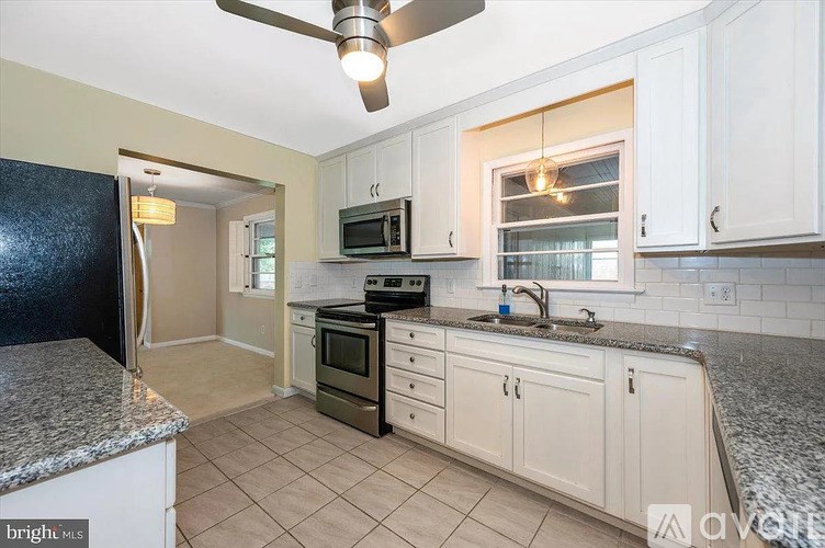A kitchen with a black refrigerator and white cabinets.