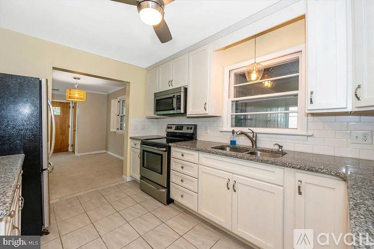 A kitchen with white cabinets and a black refrigerator.
