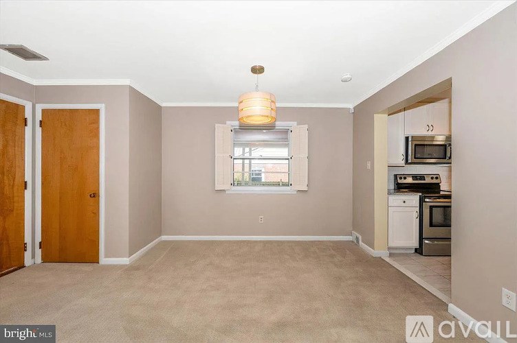 A bright living room with a window and a door leading to another room.