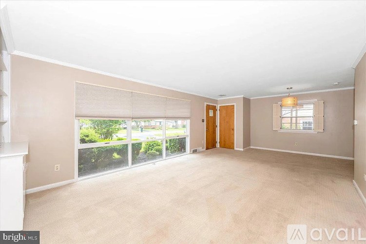 A spacious room with a fireplace on the left and a sliding glass door leading to a balcony.