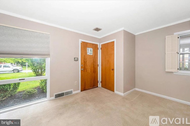 A room with a wooden door and a window with blinds.