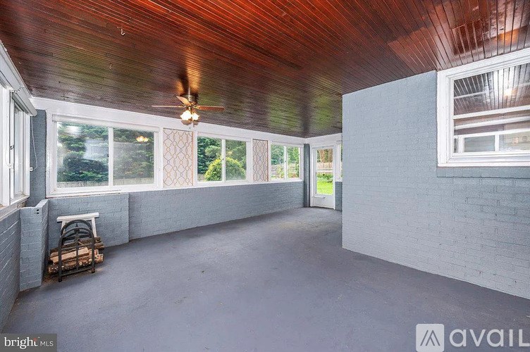 A room with a ceiling fan and large windows.