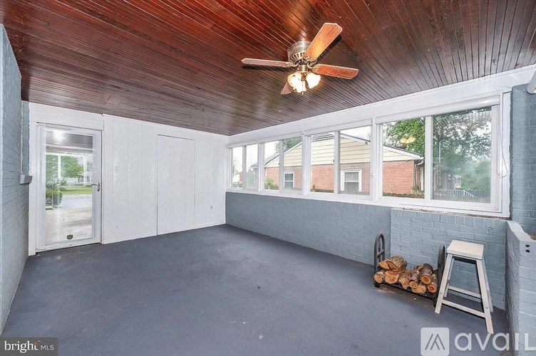 A room with a ceiling fan and a stack of wood.
