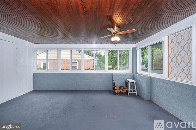 A room with a ceiling fan and a window with a view of a building.