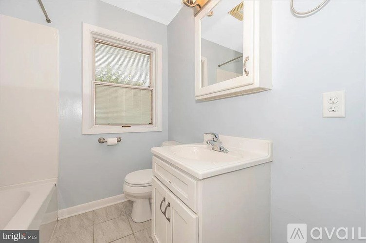 A white bathroom with a toilet, sink, and mirror.
