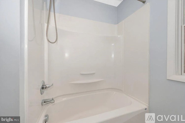 A white bathtub with a shower head and faucet.