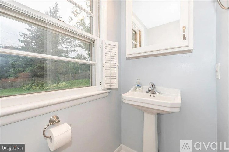 A bathroom with a white sink and a window with blinds.