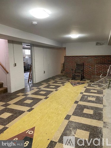 A room with a brick wall and a tiled floor with a yellow stripe down the middle.