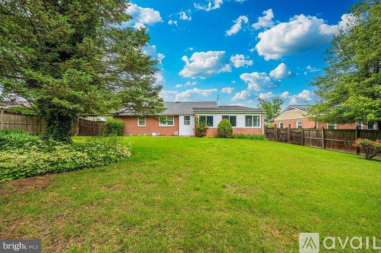 A backyard with a house, a fence, and a well-maintained lawn.
