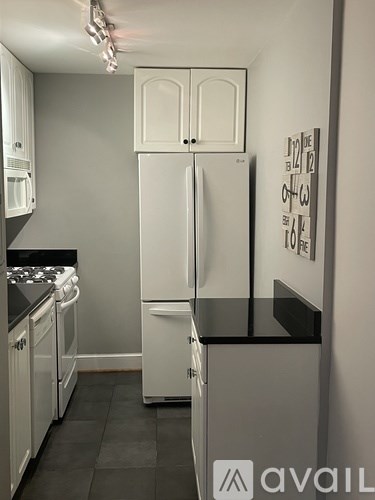 A white refrigerator stands in a kitchen with a black counter.