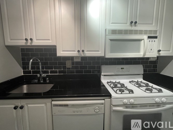 A kitchen with white cabinets and a black countertop.