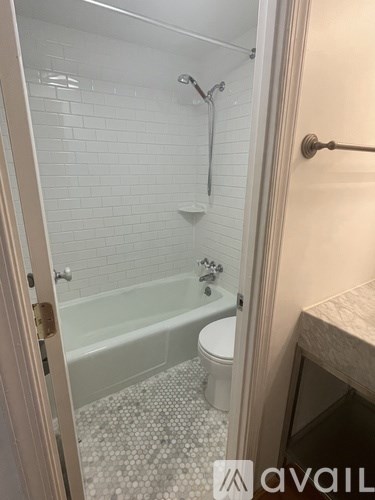 A bathroom with a white tiled shower and a white toilet.