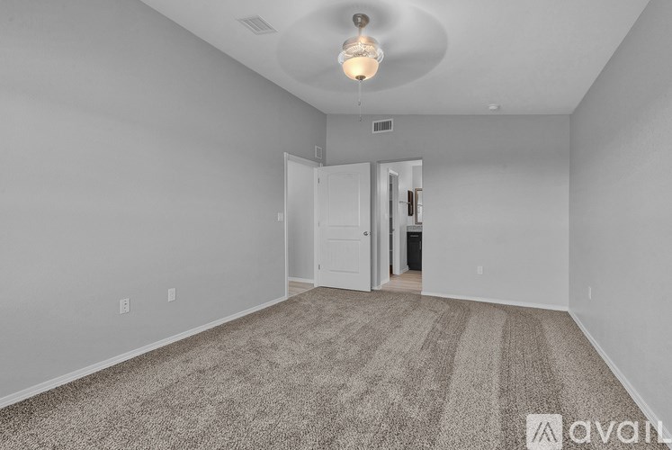 A carpeted room with a doorway leading to another room.