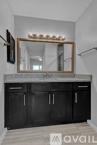 A bathroom with a marble countertop and a mirror with lights.