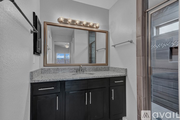A bathroom with a granite countertop and a mirror with lights above it.