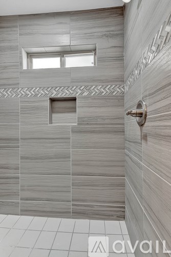 A bathroom with a tiled wall and a small window.