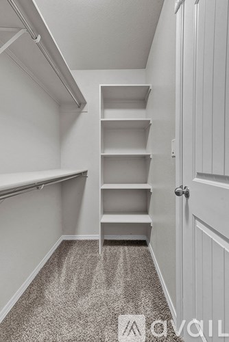 A white hallway with a carpeted floor and a door on the right.