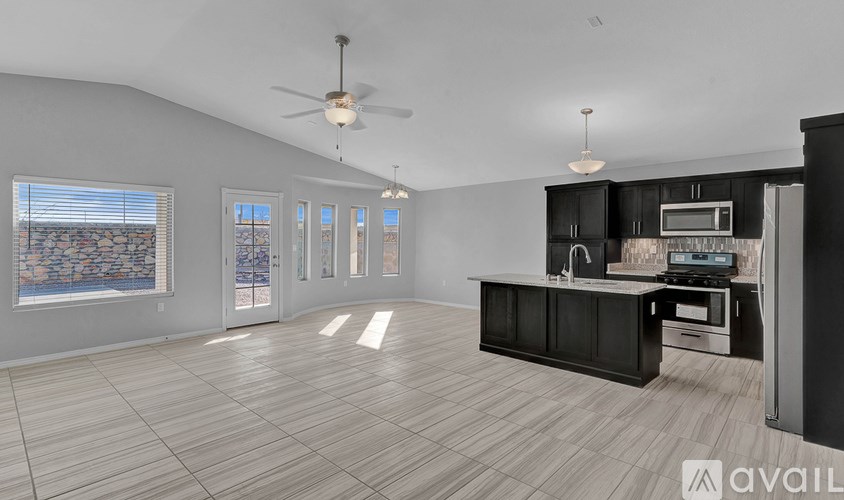 A spacious kitchen with a black countertop and a ceiling fan.