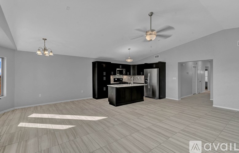 A spacious room with a kitchenette and a ceiling fan.