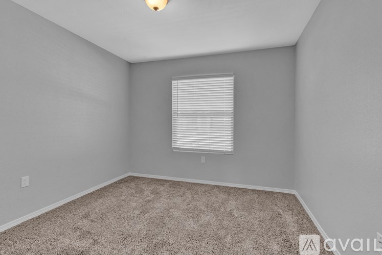 A room with a carpeted floor and a window with blinds.