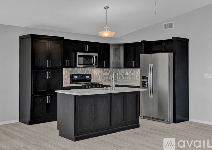 A modern kitchen with black cabinets and stainless steel appliances.
