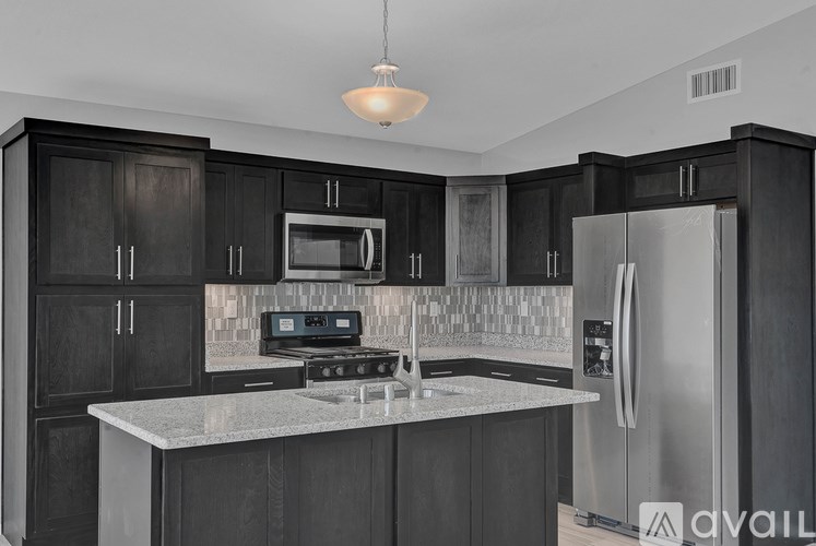 A modern kitchen with dark wood cabinets and stainless steel appliances.