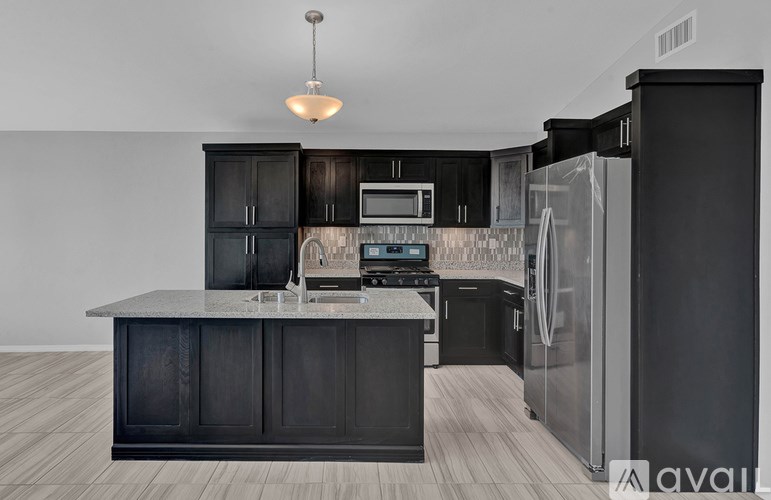 A kitchen with black cabinets and a granite countertop.