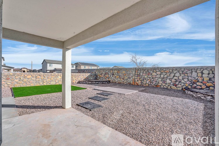 A patio with a stone wall and a green mat.