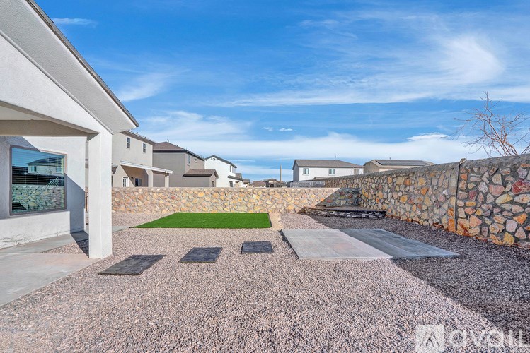 A modern house with a stone wall and a gravel driveway.