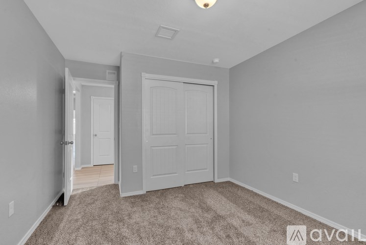 A room with a carpeted floor and two doors, one of which is open.