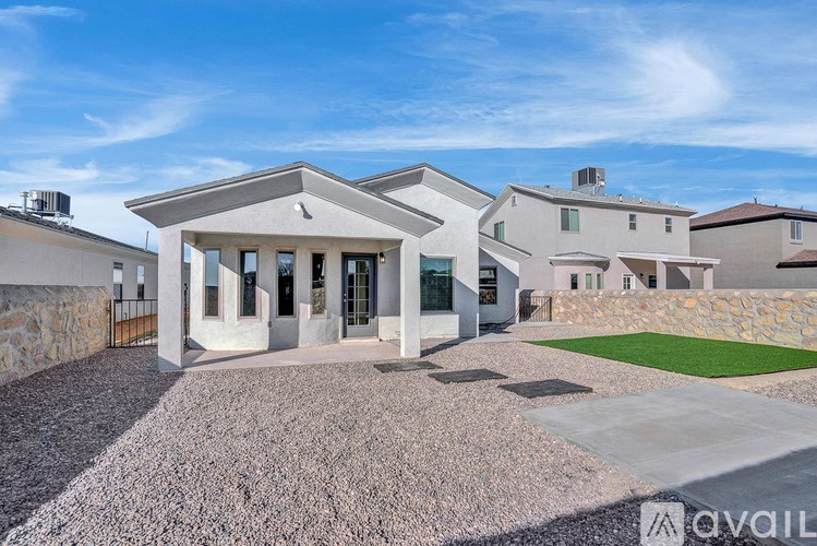 A modern house with a gravel driveway and a stone wall.