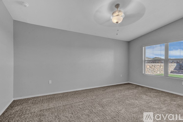 A room with a carpeted floor and a window with blinds.