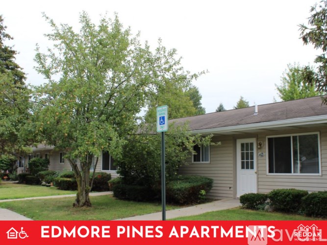 A sign for Edmore Pines Apartments is in front of a house.