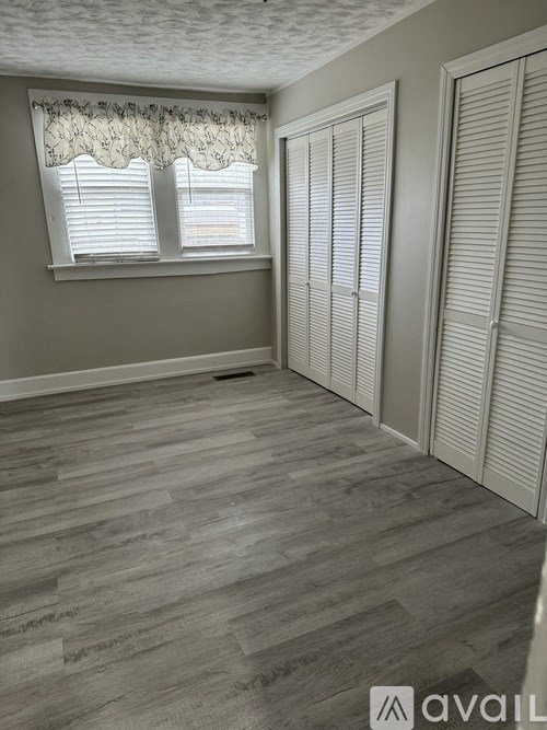A room with a window and a wooden floor.