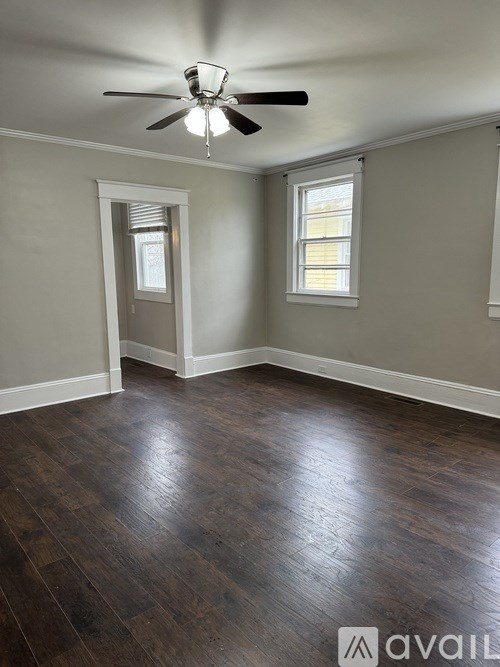 A room with a ceiling fan and wooden flooring.