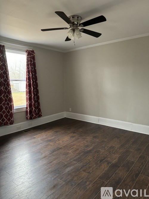 A room with a ceiling fan and wooden flooring.