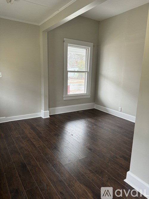A room with wooden flooring and a window.