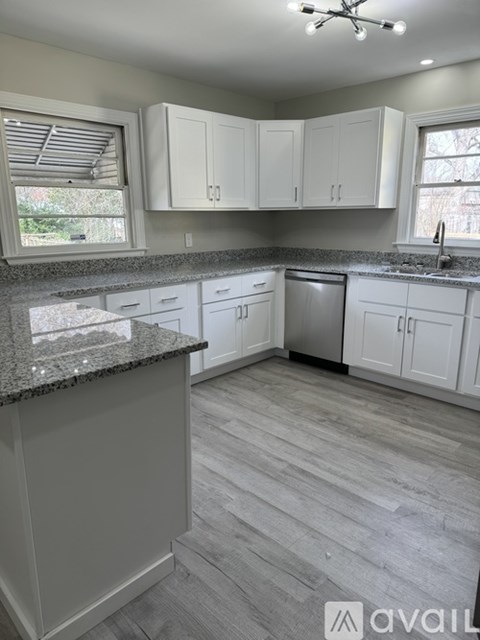 A kitchen with white cabinets and a granite countertop.