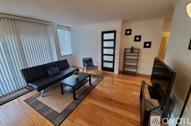 A living room with a black sofa and a wooden floor.