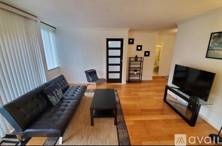 A black leather sofa sits in a living room with a television and a coffee table.