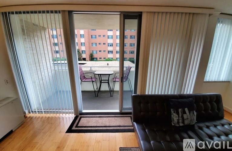 A living room with a black couch and a sliding glass door leading to a balcony.
