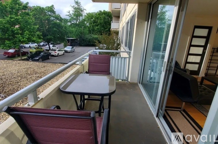 A balcony with a table and chairs overlooking a parking lot.