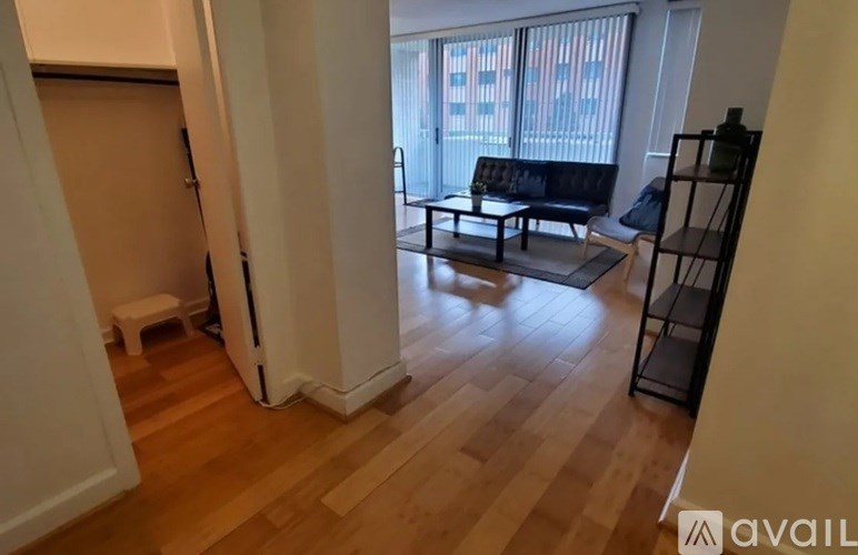 A living room with a black sofa and a wooden floor.
