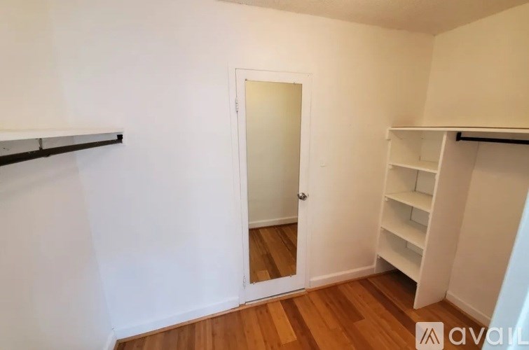 A room with a white door and a mirror on the wall.