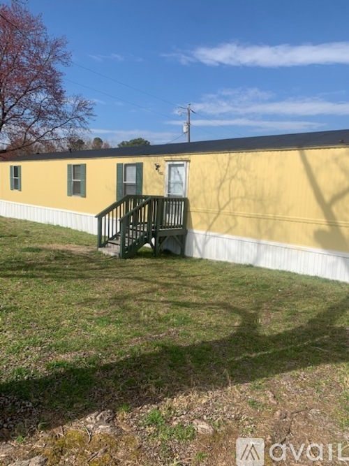 A yellow building with a green door and a black railing.