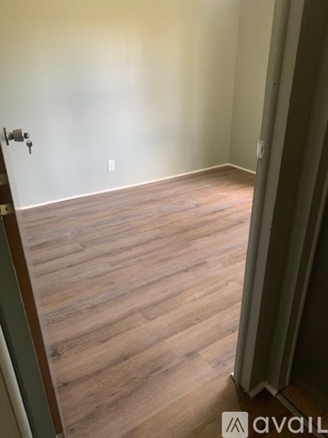 A room with wooden flooring and a door with a keyhole.