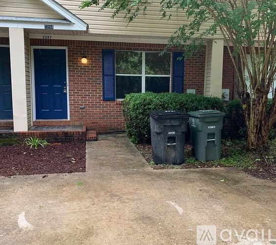 A house with a blue door and two green bins in front.